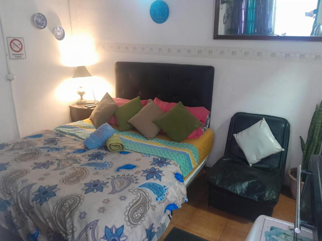 a bedroom with a bed with colorful pillows and a chair at Aires del Atlántico Sur in Burzaco