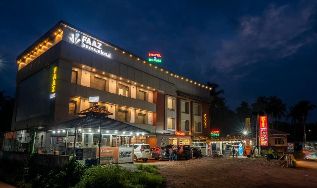 a building with cars parked in a parking lot at night at Hotel Faaz international in Thottada