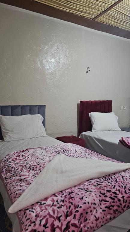 a bedroom with two beds with a purple blanket at Dar chez bassou in Imilchil