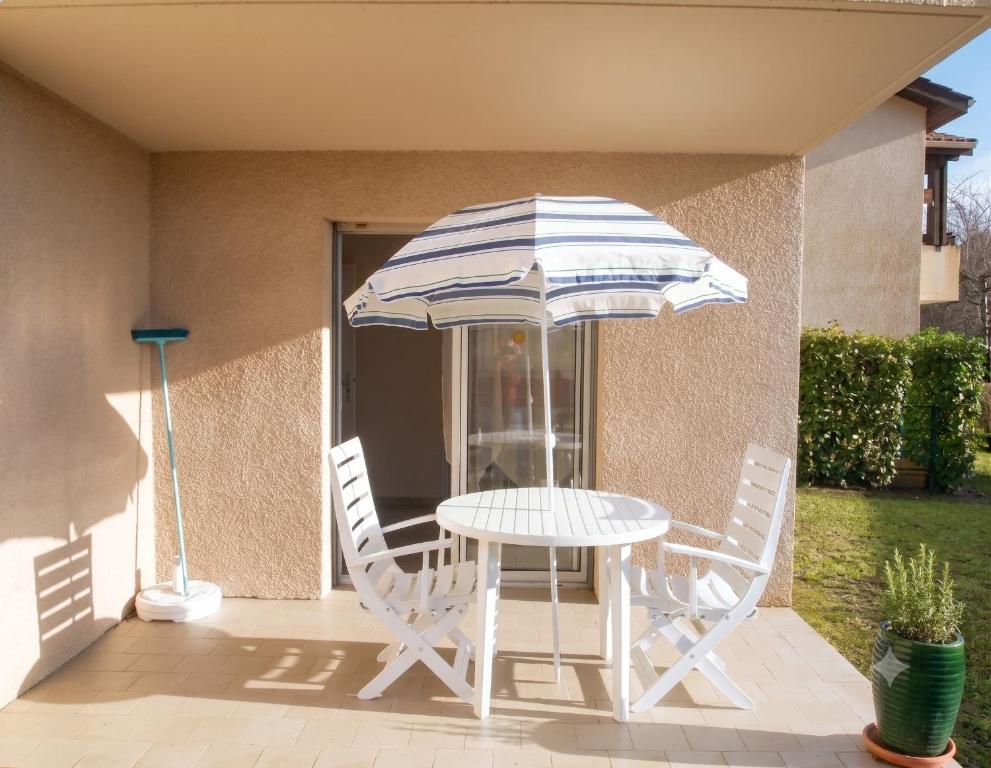 a table and chairs with an umbrella on a patio at Appartement Soleil d'Oc 5 in Cazaubon