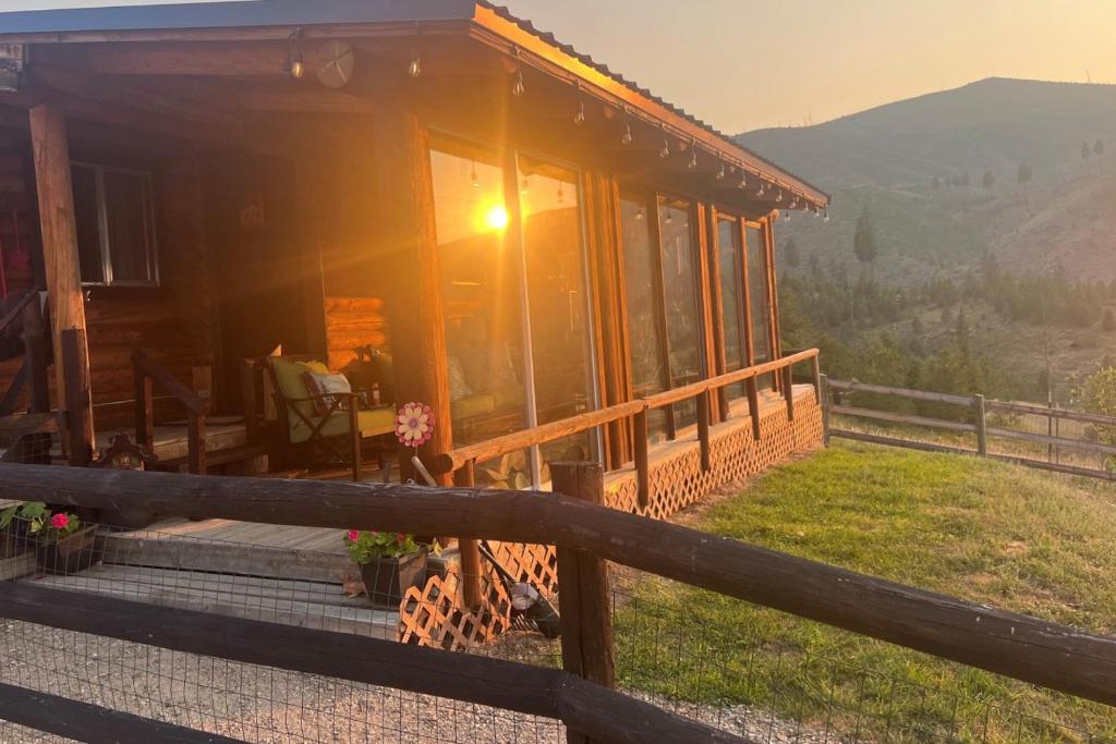 a house on a hill with the sun setting at Cozy Cabin Oxen-Le-Fields Montana in Conner