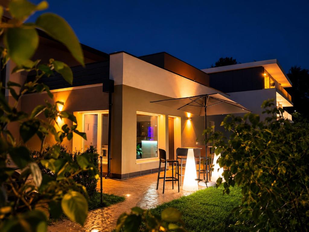 a house with an umbrella in the backyard at night at Luxea Guest House - B&B Treviso in Preganziol