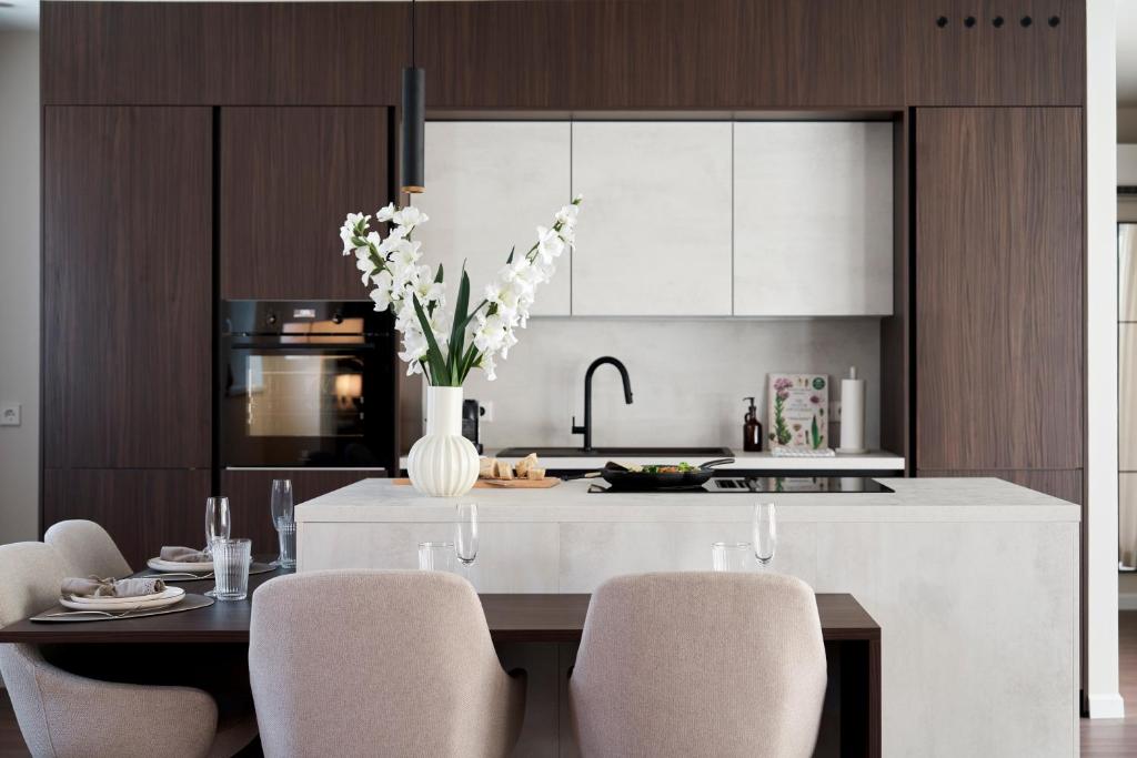 a kitchen with a table with chairs and a vase of flowers at Stadtmauerloft - Premium Apartment in Eisenstadt