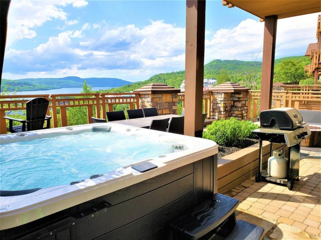 a jacuzzi tub on a patio with a grill at Tremblant Prestige - Altitude 170-1 in Mont-Tremblant