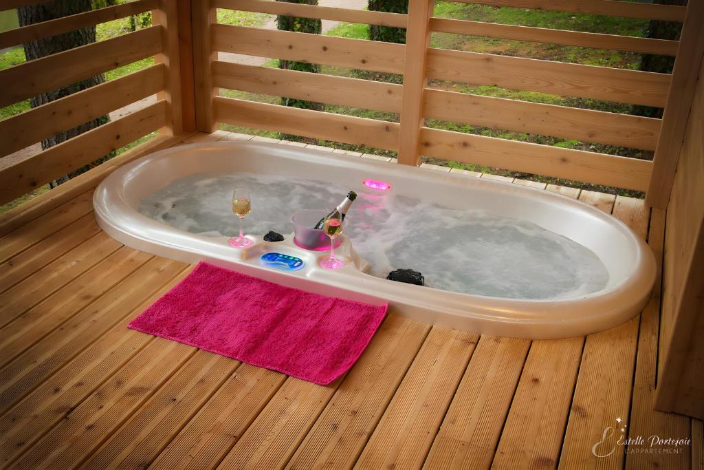 a jacuzzi tub with drinks and a bottle of champagne at La Cabane Spa De Céline in Voussac