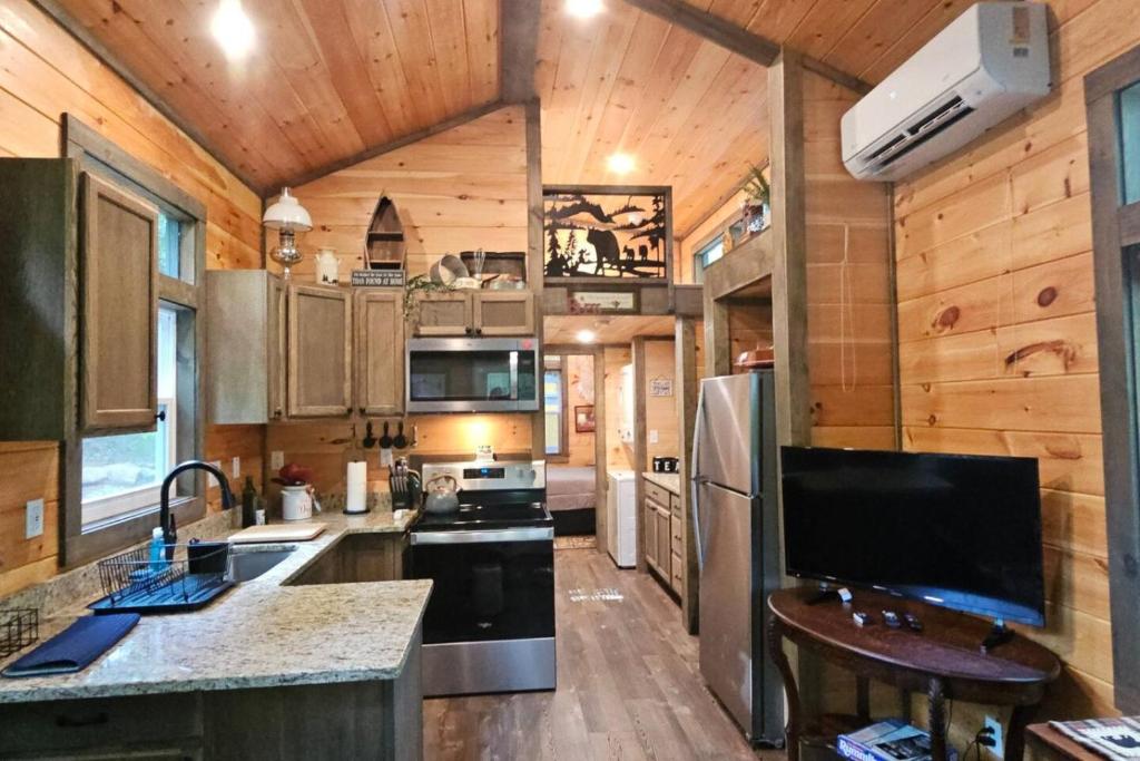 a kitchen in a log cabin with a sink and a refrigerator at Amazing Mountain View Tiny House in Hayesville