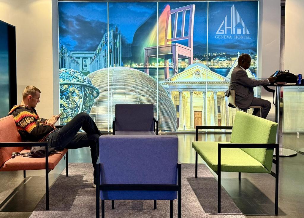 two people sitting in chairs in a room with a poster at Geneva Hostel in Geneva