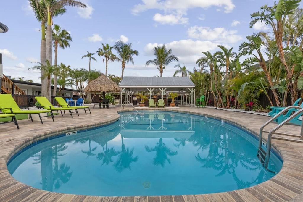 a swimming pool with chairs and palm trees at Coconut Grove Resort in Clearwater Beach