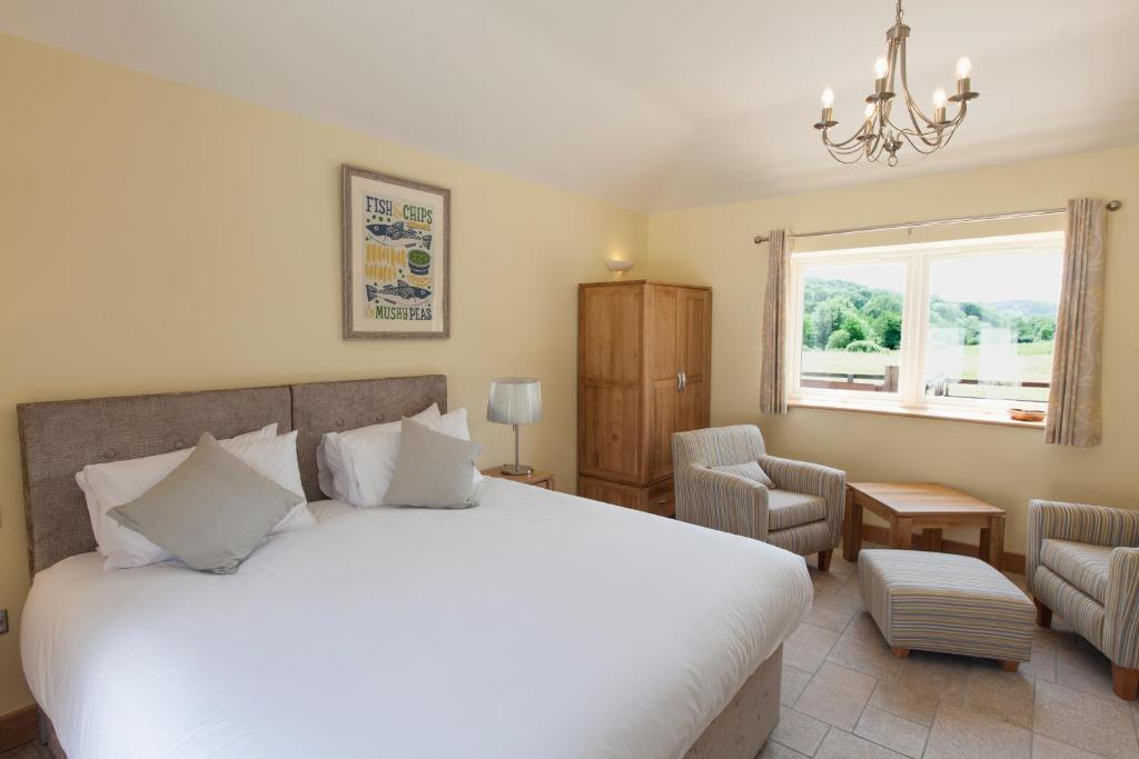 ein Schlafzimmer mit einem großen weißen Bett und einem Fenster in der Unterkunft Mincombe Barn Bed & Breakfast in Sidbury