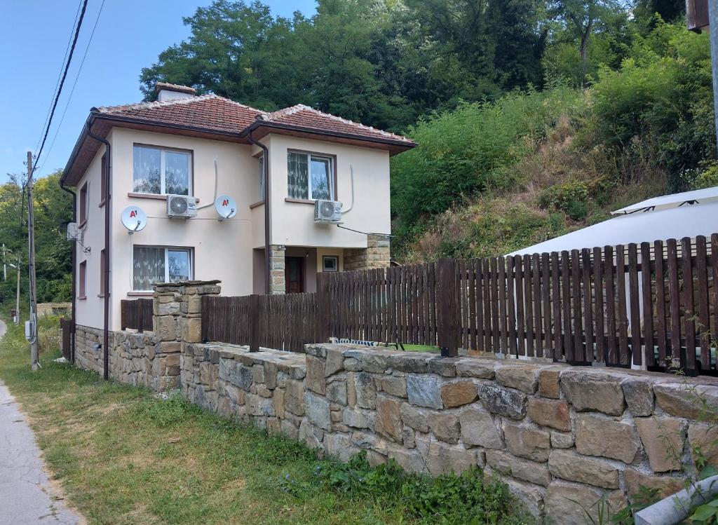 a house behind a stone wall with a fence at Къща Владислав in Radevtsi