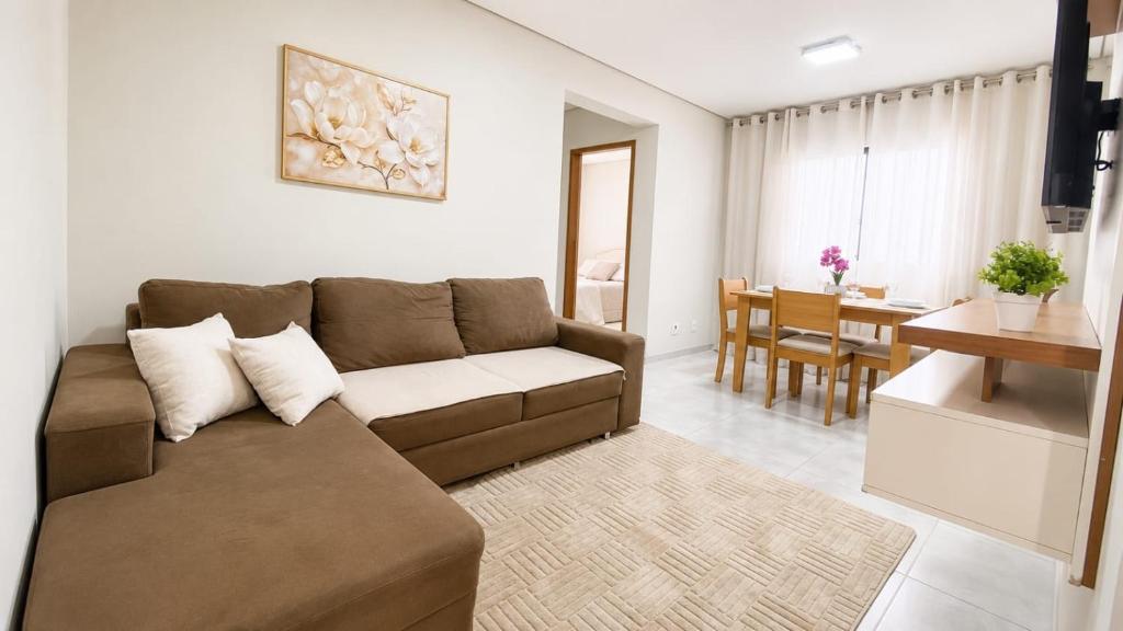 a living room with a couch and a dining room at Apartamento Aconchegante de 02 Quartos in Cuiabá