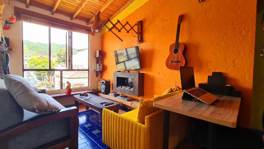 a living room with an orange wall with a guitar at Apartamento Acogedor en el Retiro in El Retiro