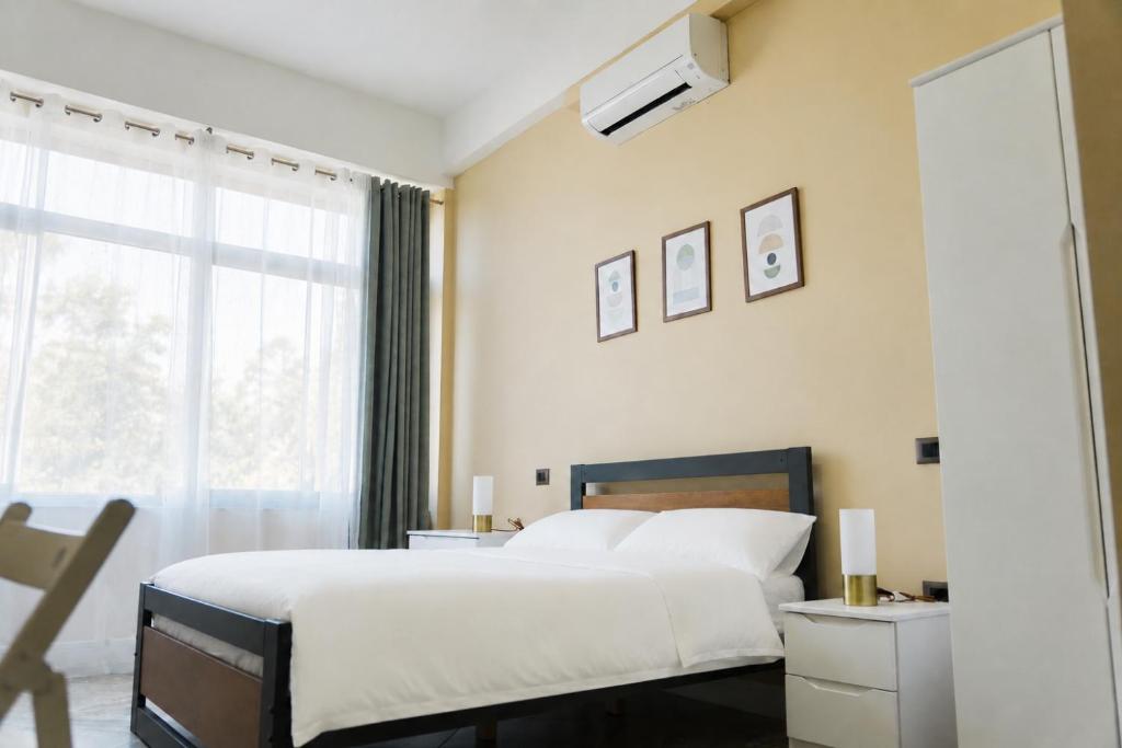 a bedroom with a large white bed and a window at Gazulli Guesthouse in Lezhë