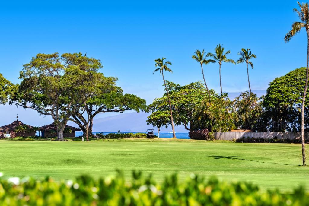 a golf course with palm trees and the ocean at Maui Eldorado Condo J123 in Kaanapali