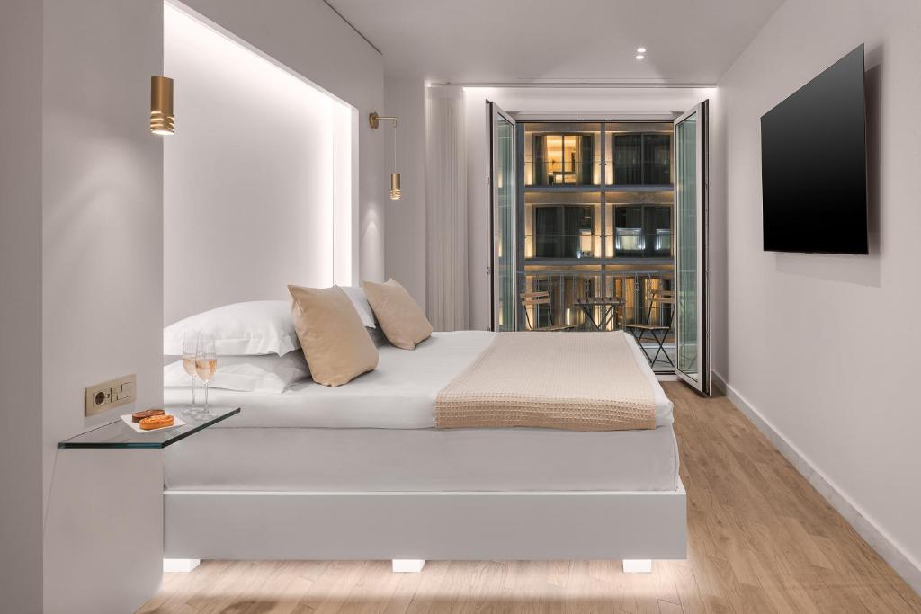 a white bedroom with a bed and a tv on a wall at White Rose Athens Residence in Athens