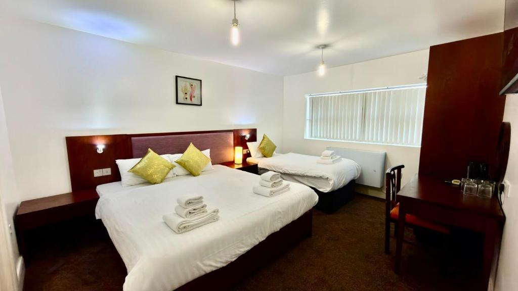 a hotel room with two beds and a desk at Hotel Blackpool in Blackpool