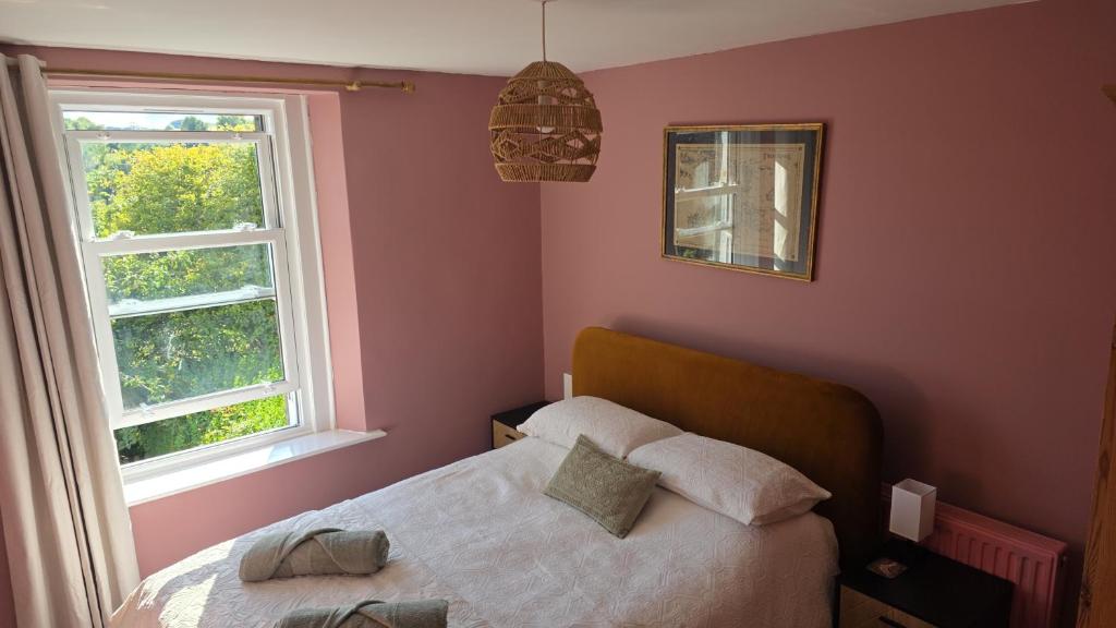 a bedroom with a bed and two windows at Lodge hill cottage in Liskeard