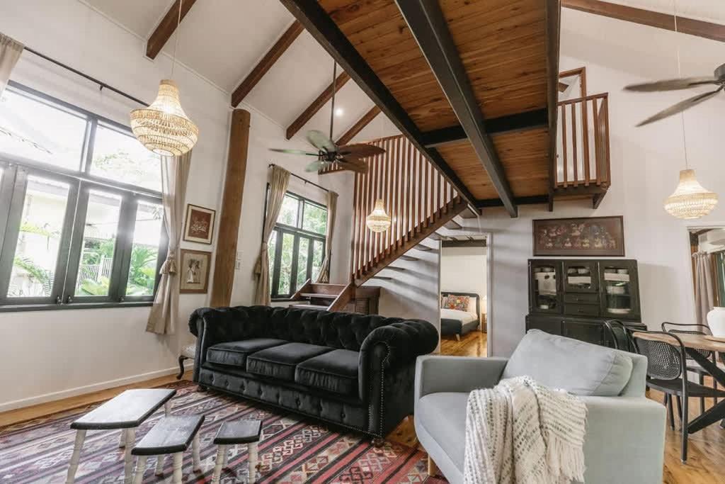 a living room with a black couch and a table at The Treehouse - Rainforest Home - Pool in Smithfield