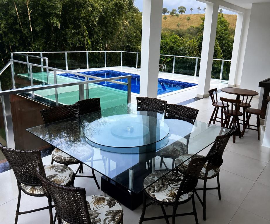 a glass table and chairs on a balcony with a swimming pool at Paraíso Escarpas do Lago 1 - Capitólio in Capitólio
