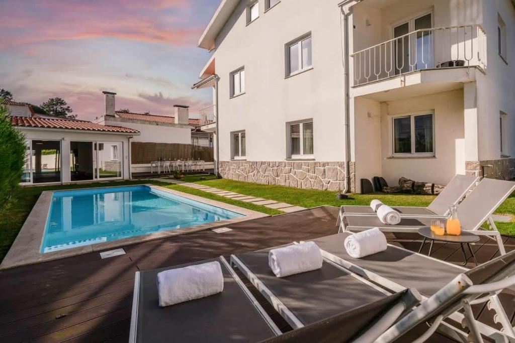 a backyard with a swimming pool and a house at Portugal Active Cabedelo Beach Lodge - Heated Pool in Viana do Castelo