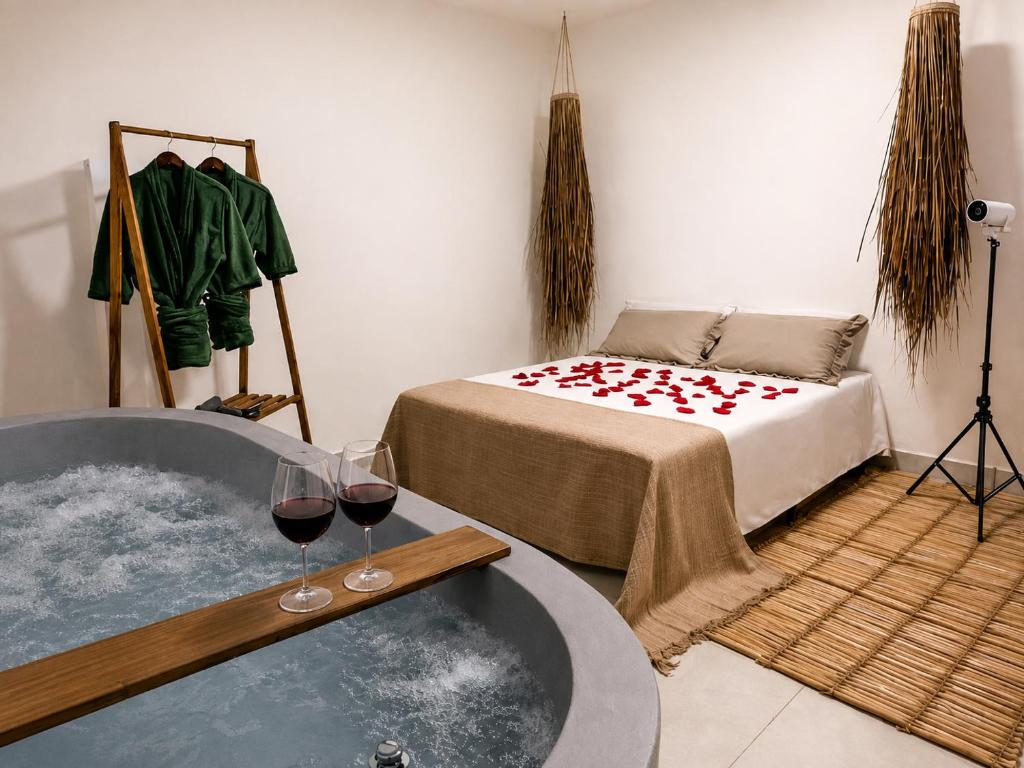 a room with a tub with two glasses of wine at Raya Beach Studios in Maresias