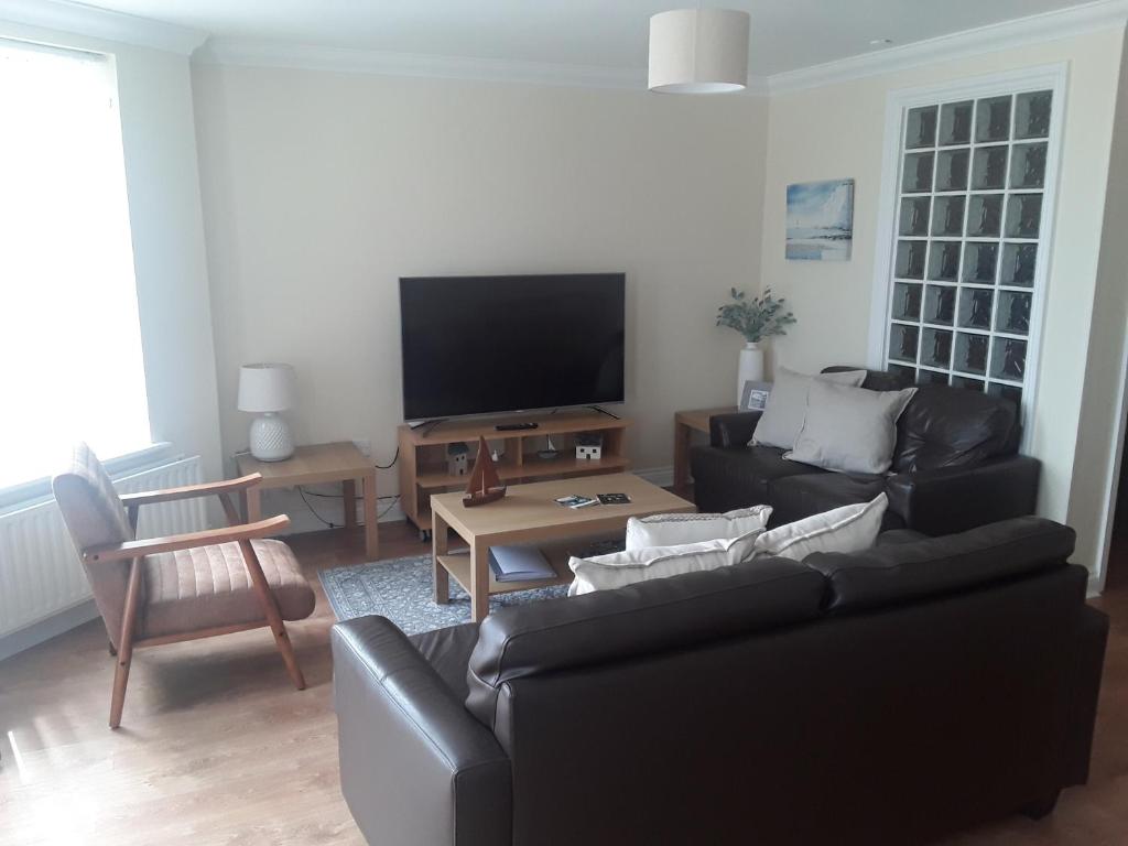 a living room with a black couch and a tv at isleofmanholidayapartment in Douglas