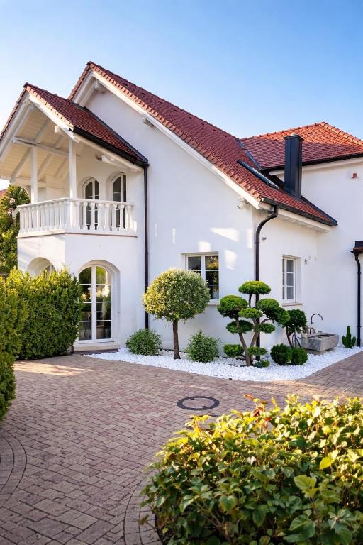 a white house with a balcony and some bushes at Villa Löwe - Heated Indoor Pool, Spa & Wellness Estate near Basel in Kandern
