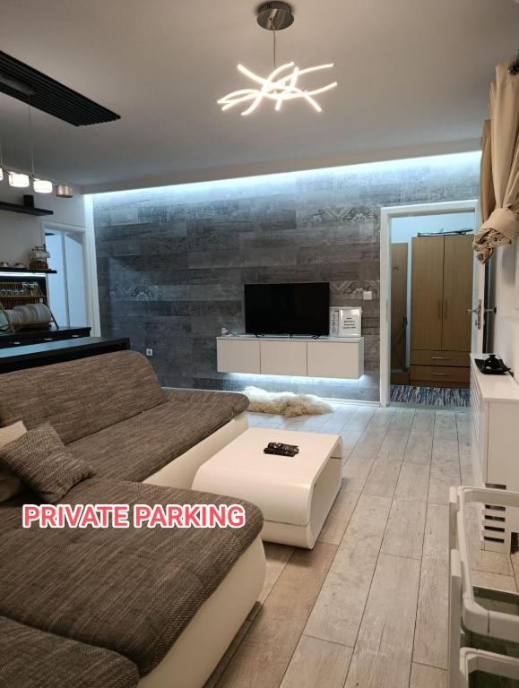 a living room with a couch and a tv at Cozy apartment with garden in Sarajevo