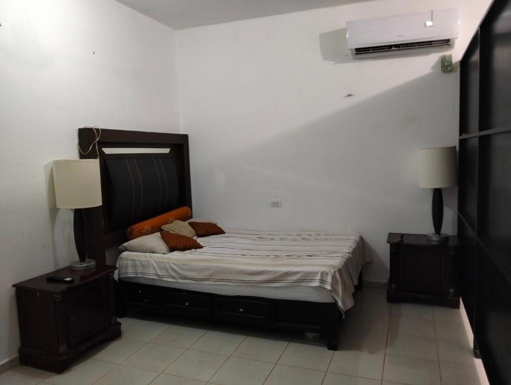 a bedroom with a bed with two night stands and two lamps at Cómo en casa in Tizimín