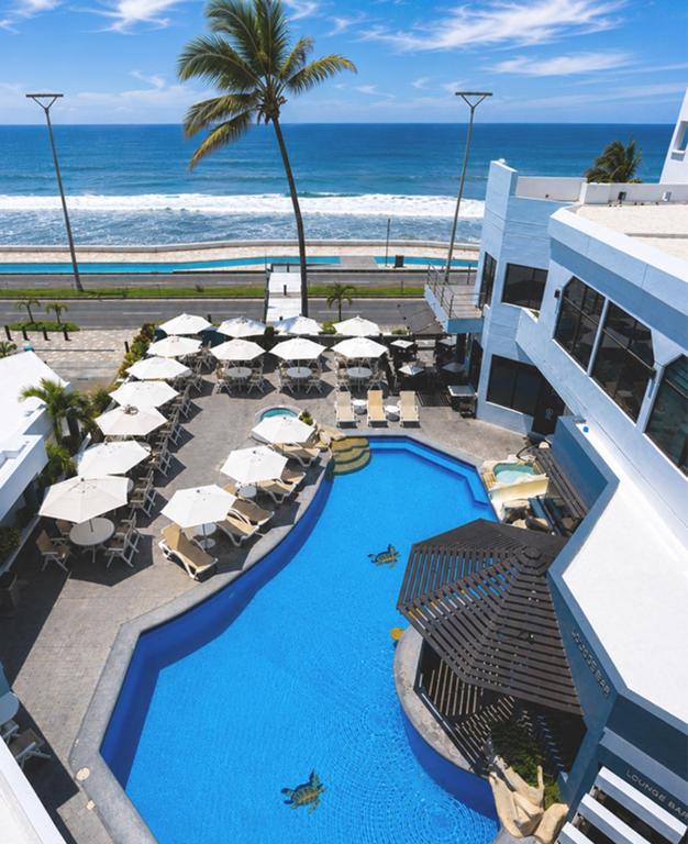 a resort with a swimming pool with umbrellas and the ocean at Olas Altas Inn Hotel & Spa in Mazatlán