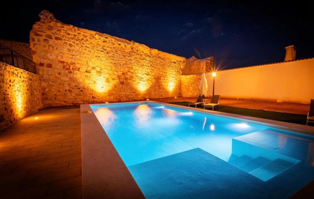 a swimming pool at night with a brick wall at La Serrería-Premium Suite Apartments & Private Jacuzzi in Belmonte