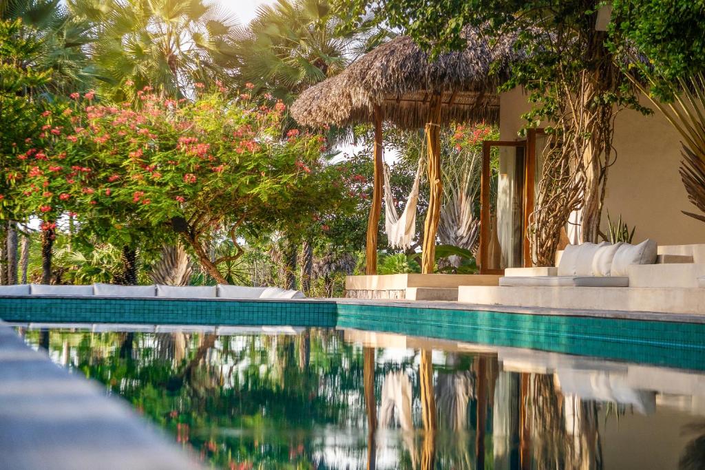 a swimming pool with chairs and a house with trees at Villa Paz - La Villa Group in Camocim
