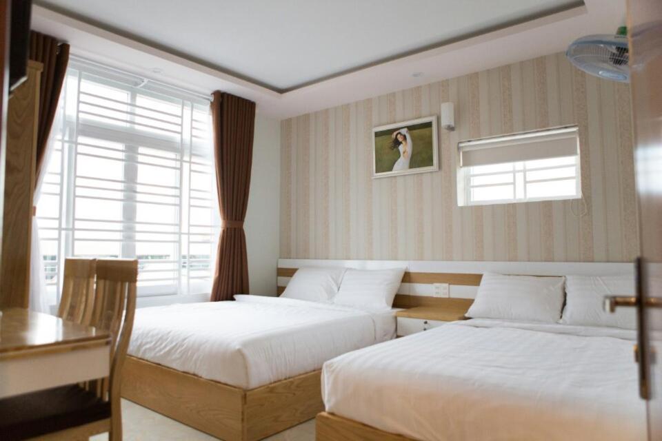 a bedroom with two beds and a table and a window at Thien Nga Hotel in Buon Ma Thuot