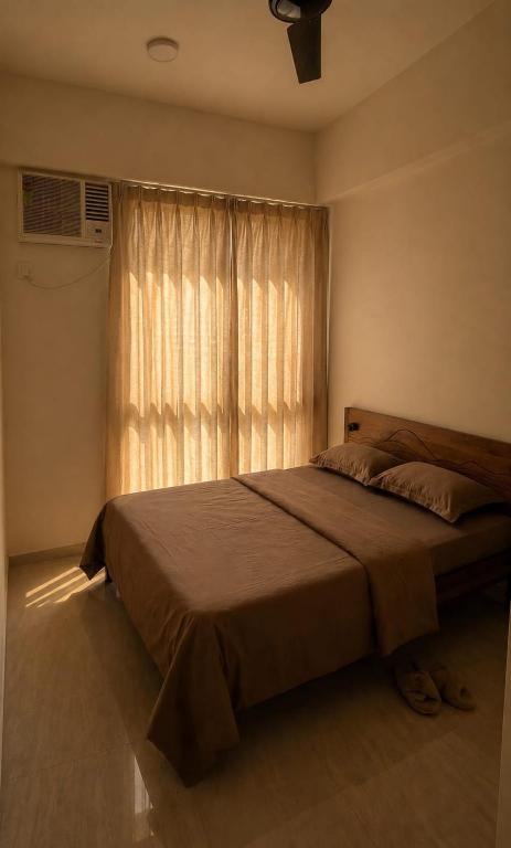 a bedroom with a large bed and a window at Lodha Crown Premium 2BHK Thane in Thane