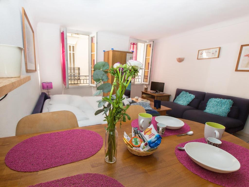 a living room with a table with a vase of flowers at Studios Alea in Cannes