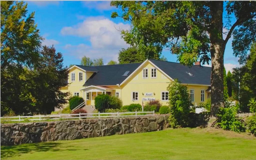 a large yellow house with a stone wall at Vitahästen in Hästveda