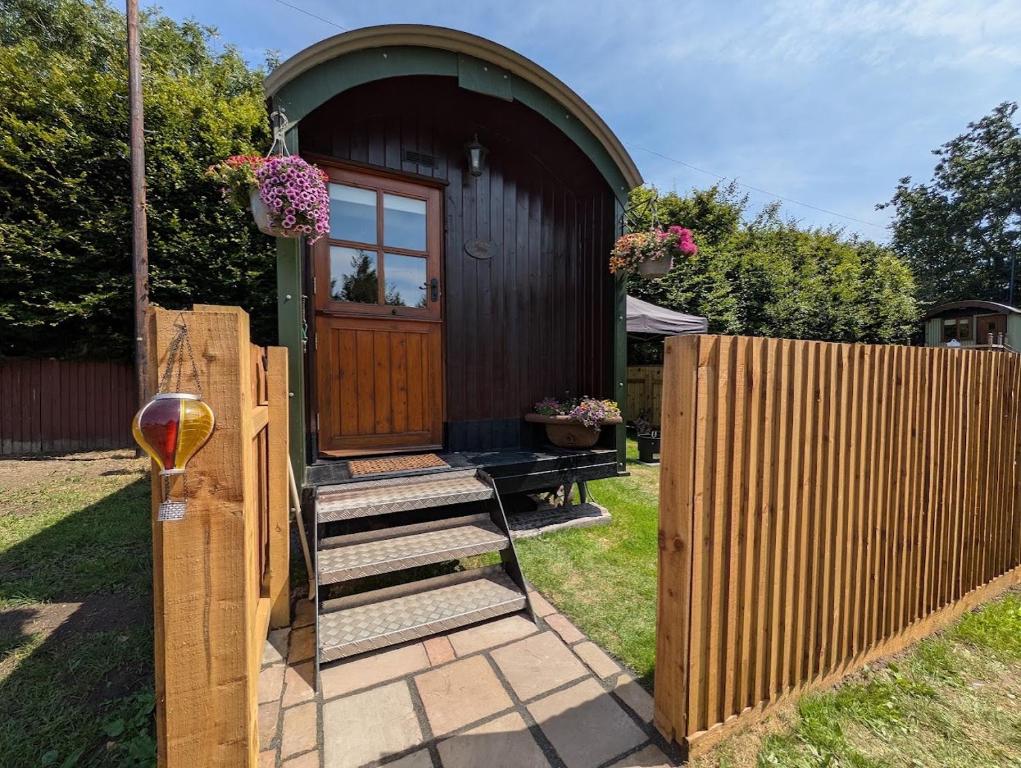 a small house with a wooden door and a fence at The Beeches in Scarisbrick
