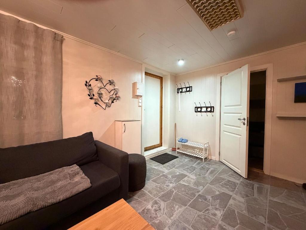 a living room with a black couch and a hallway at Apparent with 2 bedrooms for rent in Kirkenes