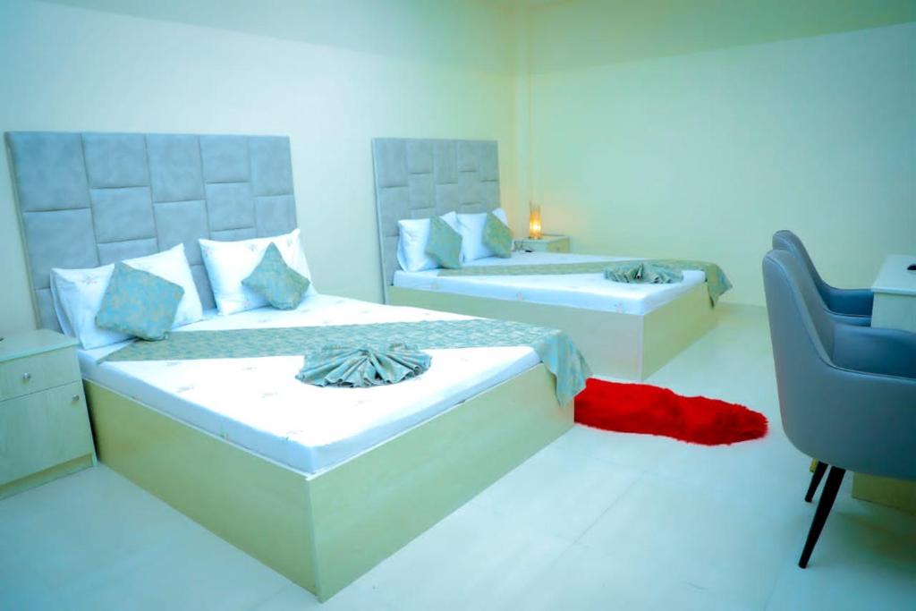 a white room with two beds and a chair at Mudha Hotel in Hargeysa