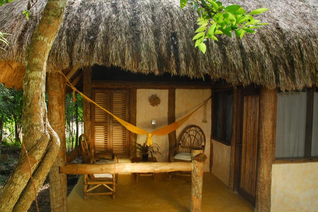 a small hut with a bed and a thatch roof at Hotel Puerta Calakmul in Conhuas