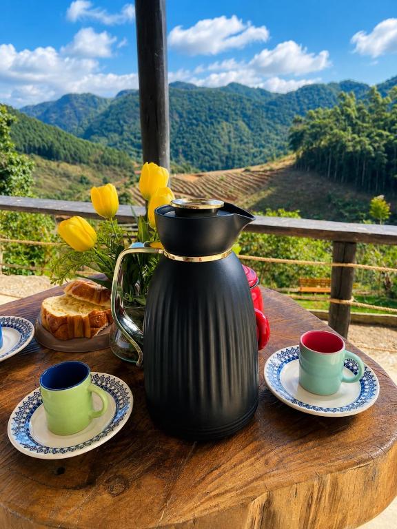 a black coffee pot sitting on a wooden table with two cups at Pousada Estância Bela Vista in Santa Teresa