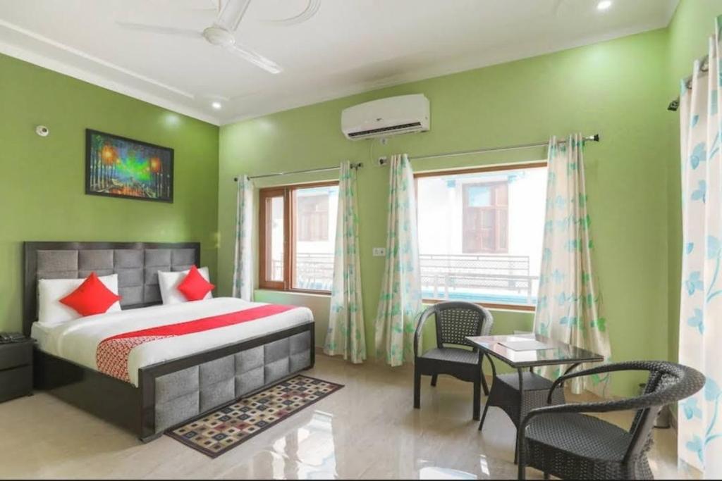 a bedroom with green walls and a bed and chairs at Elite HomeZ in Greater Noida