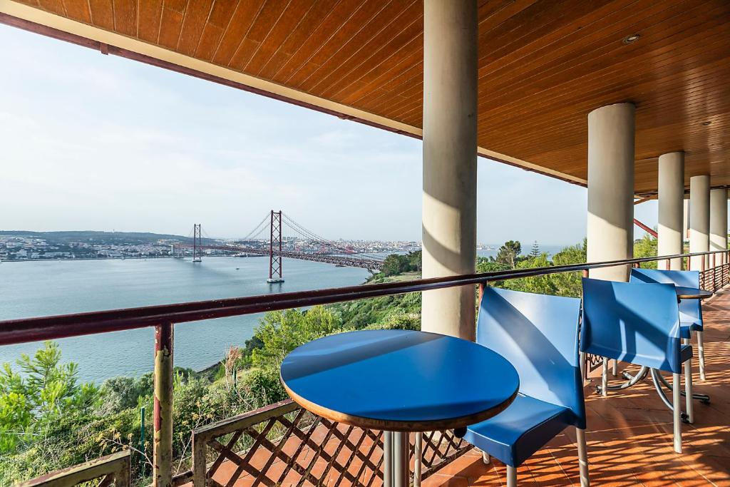 a balcony with blue chairs and a view of the golden gate bridge at HI Almada - Pousada de Juventude in Almada