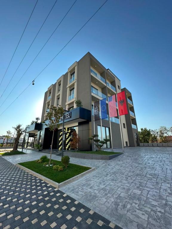 a building with two flags in front of it at Hotel New City Tirana in Kamëz