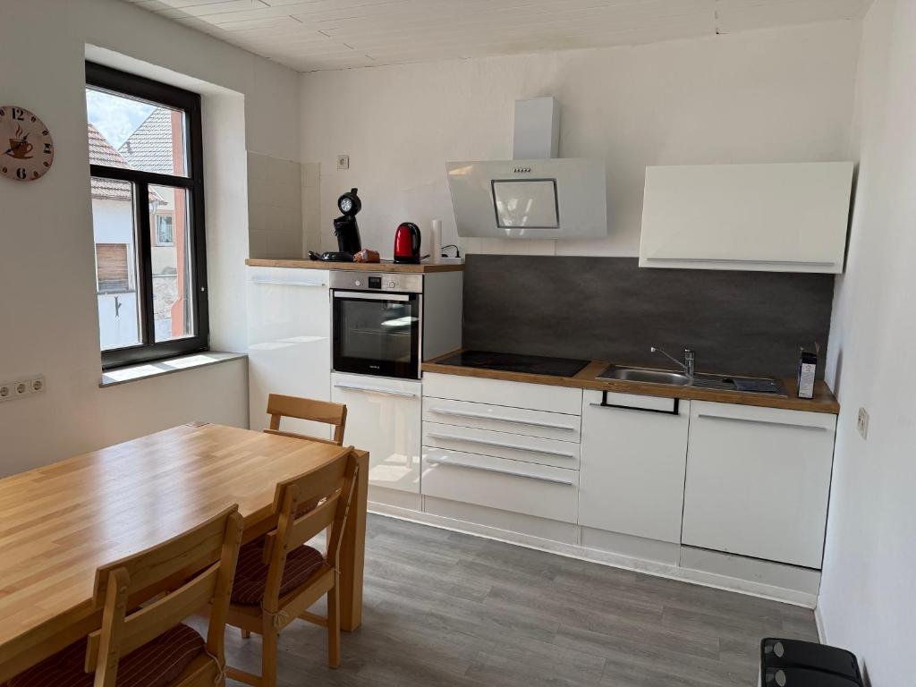 a kitchen with white cabinets and a wooden table at Reden in Illingen