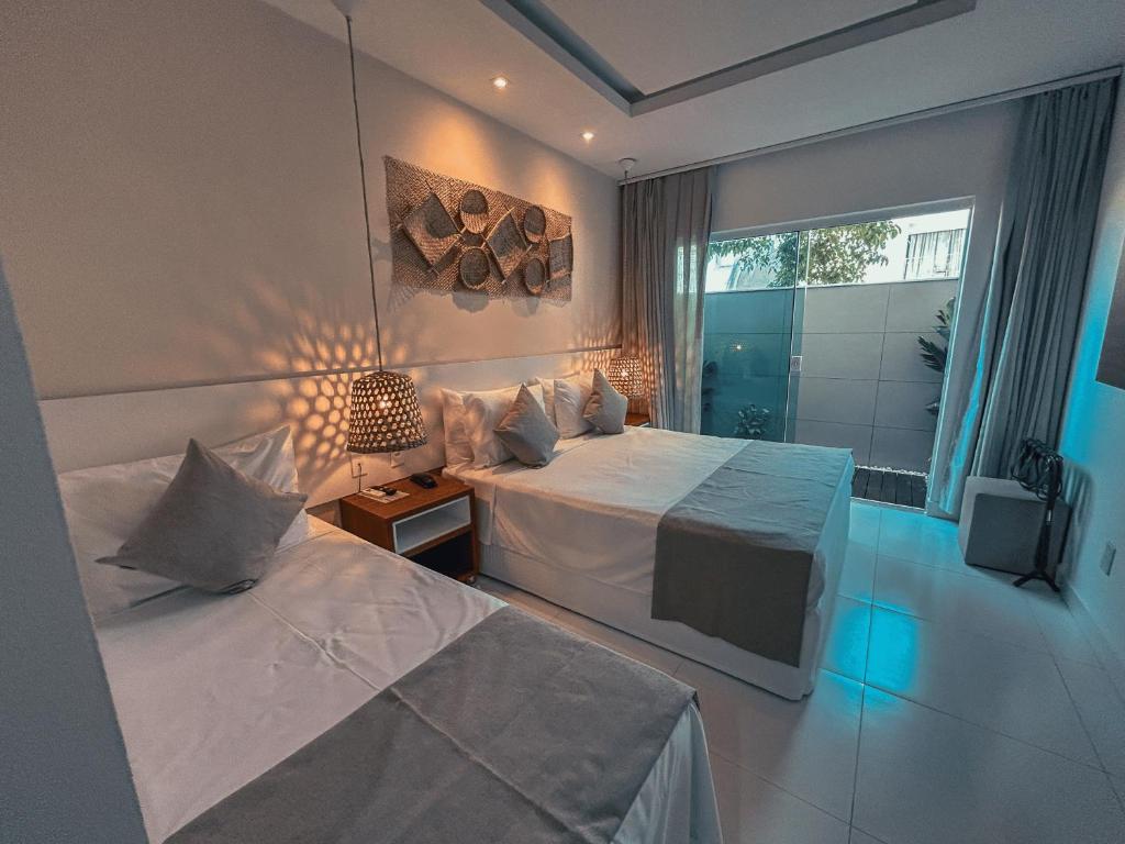 a hotel room with two beds and a window at Hotel Paradiso del Sol in Cabo Frio
