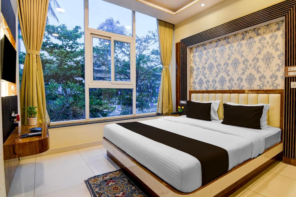 a bedroom with a large bed in a room with windows at Super Townhouse Hotel All In One in kolkata