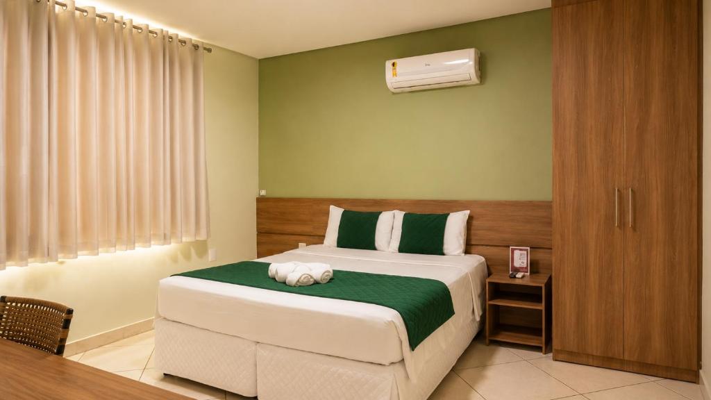 a bedroom with a bed with a green and white blanket at Domus Hotel Cidade Nobre - Ipatinga in Ipatinga