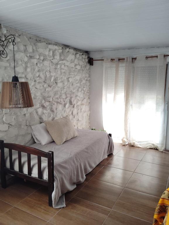 a bedroom with a bed and a stone wall at Estancia serena in Guichón