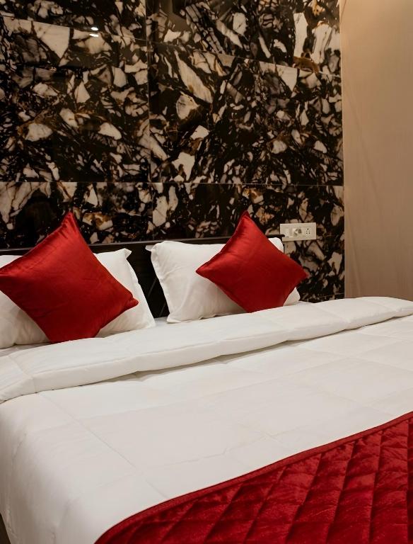 a bed with red and white pillows on it at Aquora Pool Stays in Pondicherry